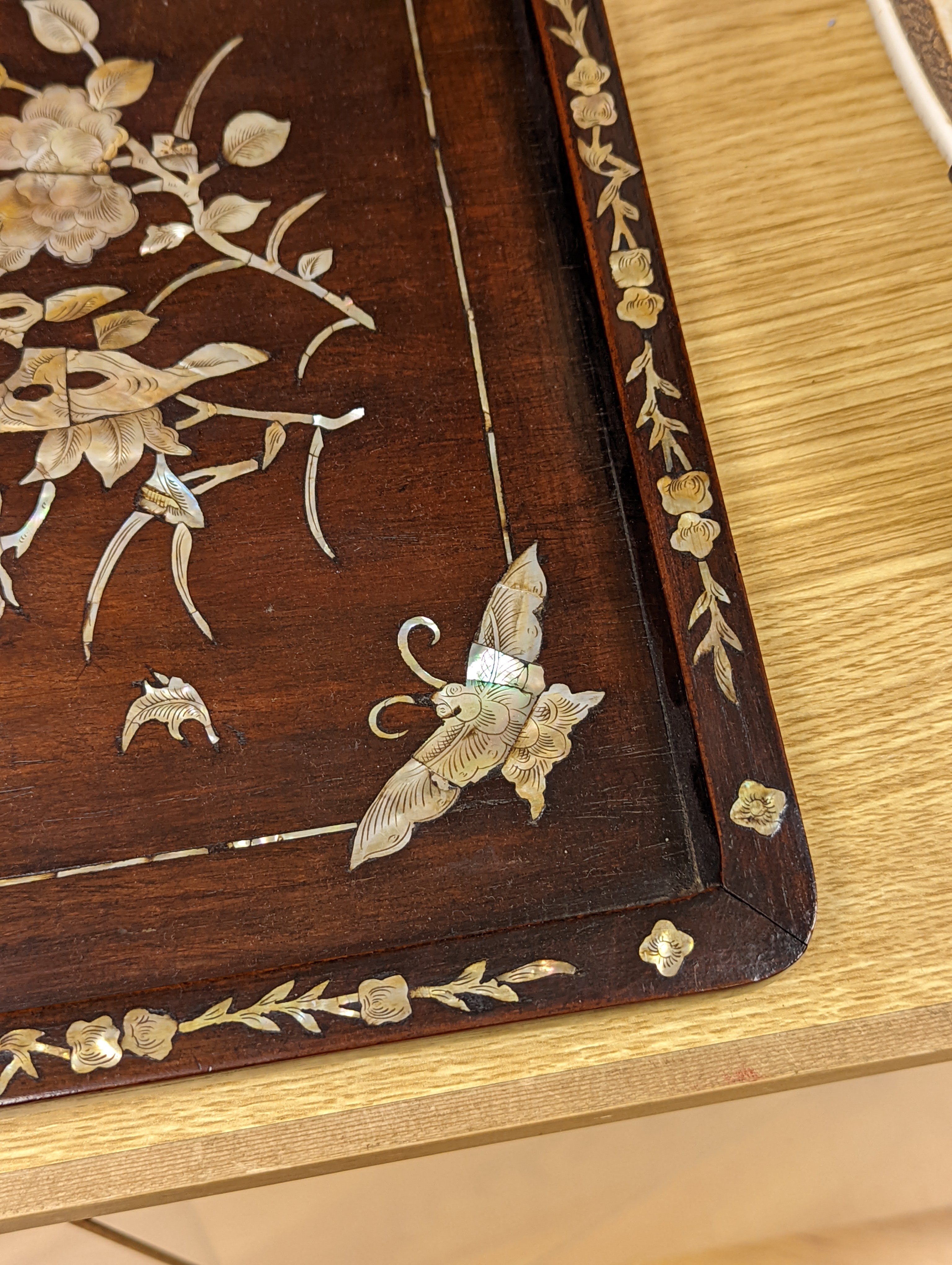 Two Chinese mother of pearl inlaid hongmu trays, the rectangular example with birds and insects amid flowers and the smaller oval example with a pavilion in a landscape within floral sprays 55x34cm